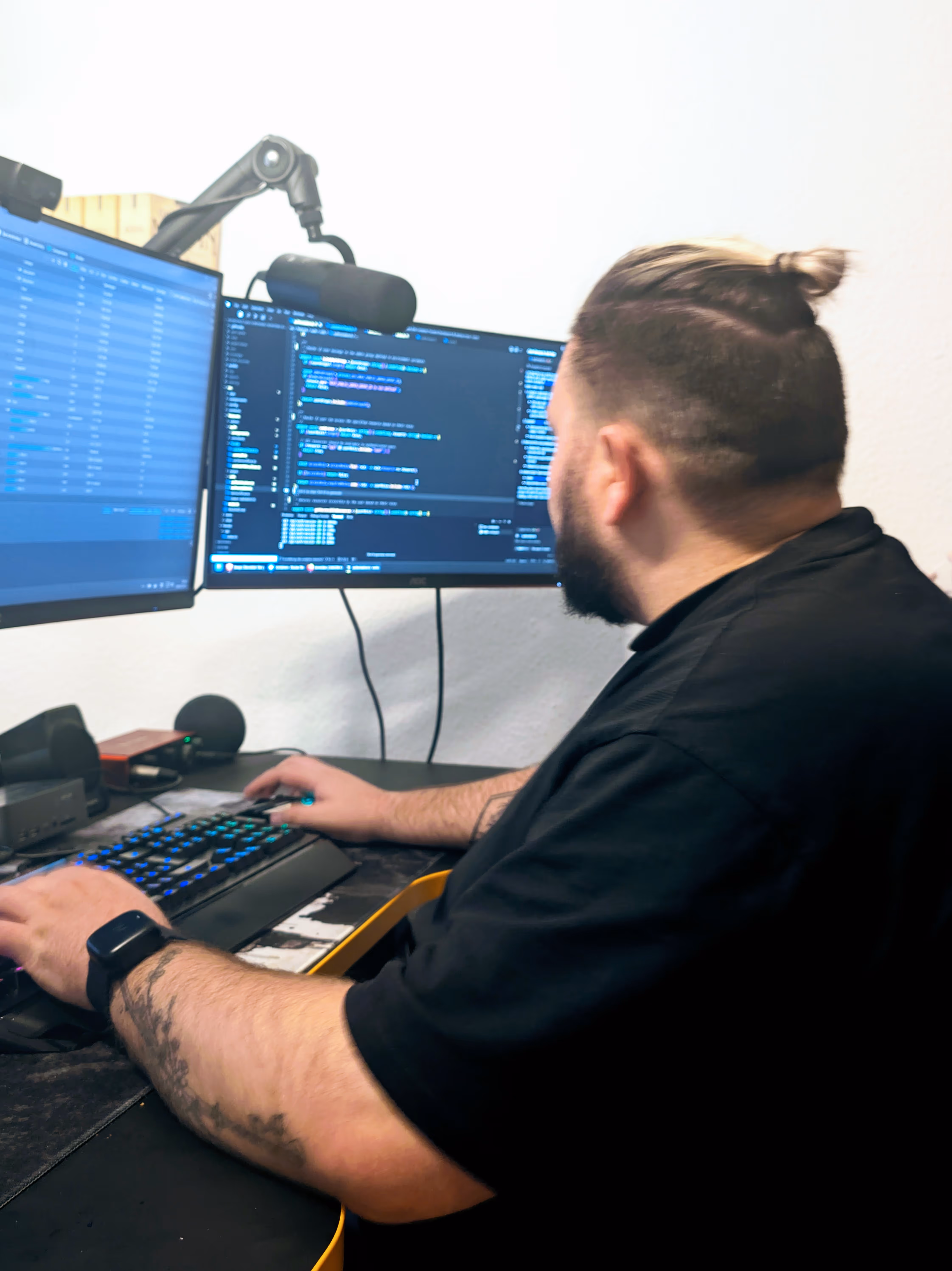 Patrik arbeitet an zwei Monitoren mit Code und Infrastruktur-Dashboards.